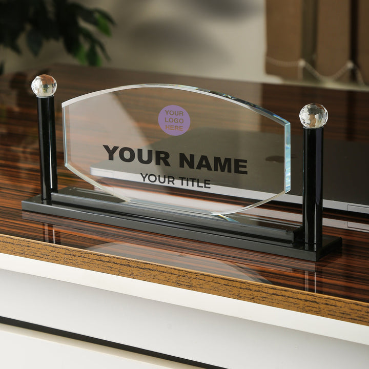 Personalized glass nameplate on a wooden surface with blurred background