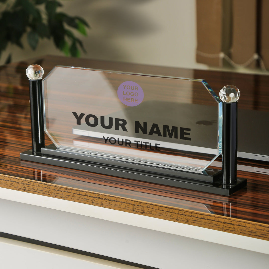 Glass nameplate with black stand on a wooden surface