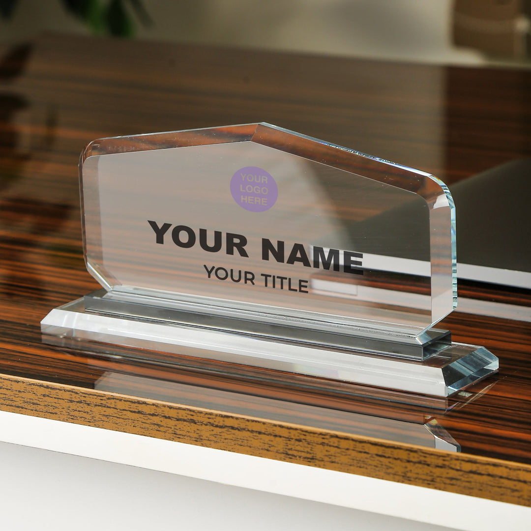 Clear glass nameplate with customizable text on a wooden surface