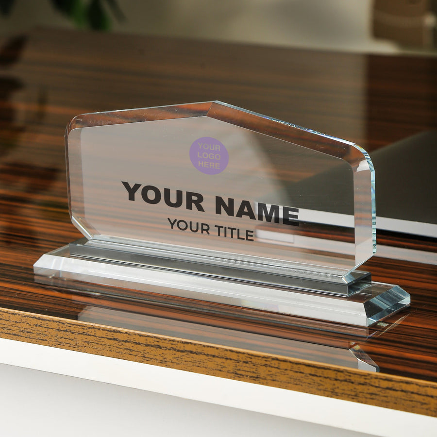 Clear glass nameplate with customizable text on a wooden surface