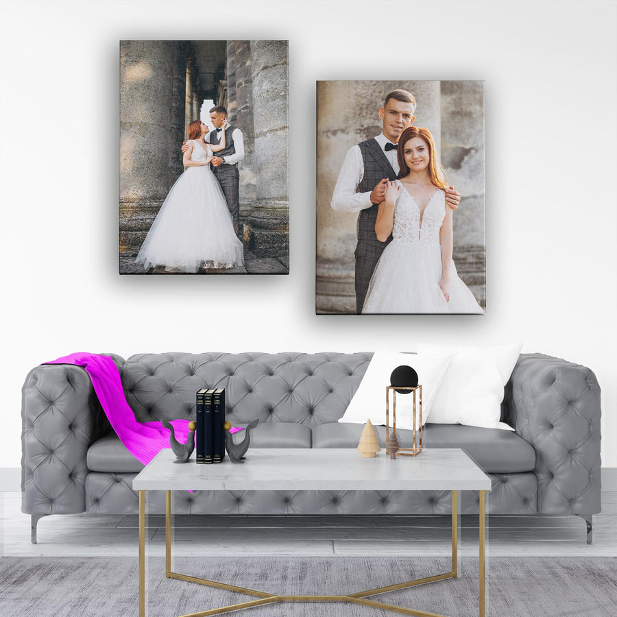 Two wedding portraits on a wall above a gray sofa with decorative items.